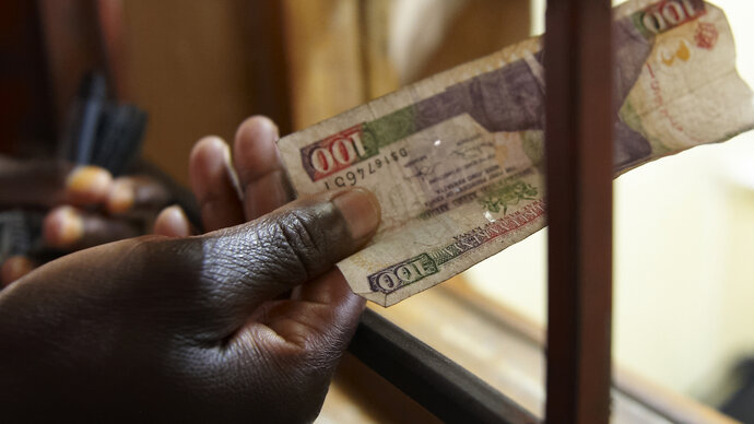 Person pays cash at health facility reception, Kenya 